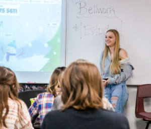 female student leaning against whiteboard with bellwork written on it