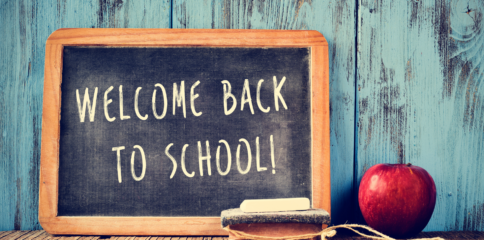 Welcome back to school on chalkboard with eraser and apple to the right