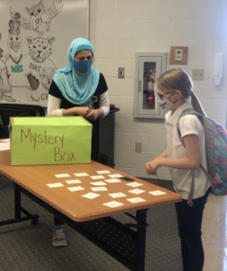 Teacher with student playing games with a mystery box on a table.
