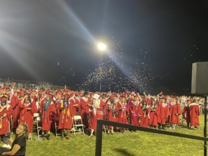SDPA Graduation 2023. Walden Grove School. Student walking in their red graduation gown with SPDA students.